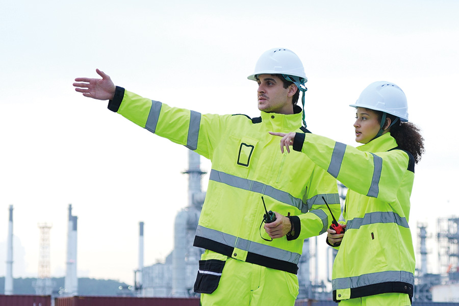 industrial-engineers-discussing-plans-refinery-site-two-safetyclad-workers-pointing-collaborating-industrial-facility-teamwork-supervision-outdoor-chemical-plant